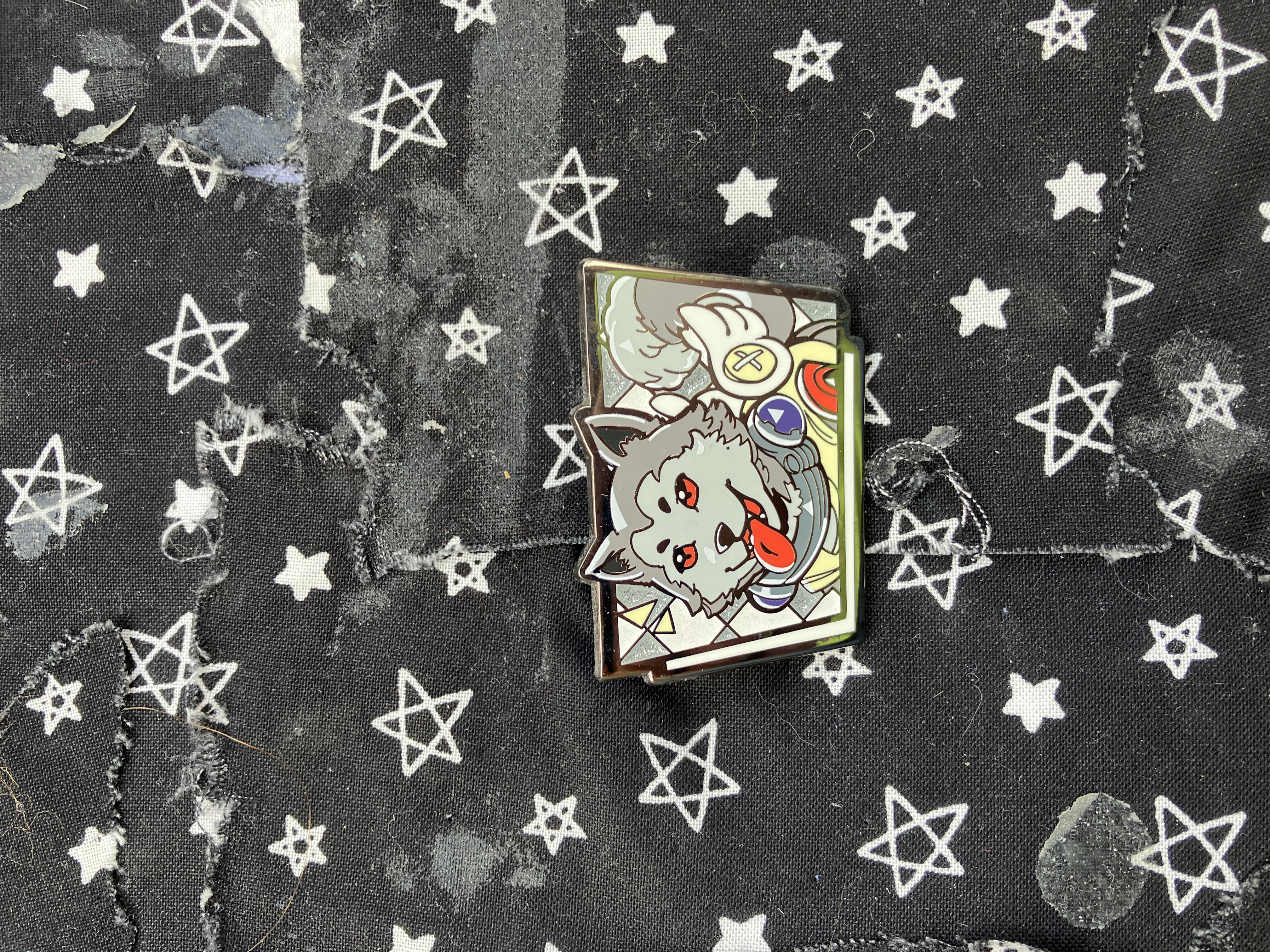 Enamel pin of Koromaru with his tongue sticking out.